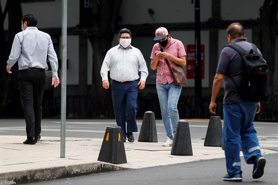 Personas con cubrebocas caminan por la Ciudad de México y utilizan su celular. Foto: EFE